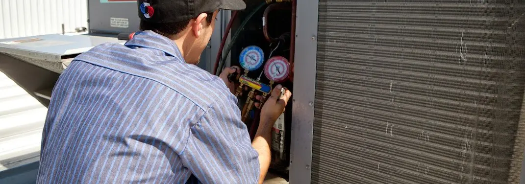 HVAC technician servicing a condenser unit in Medina